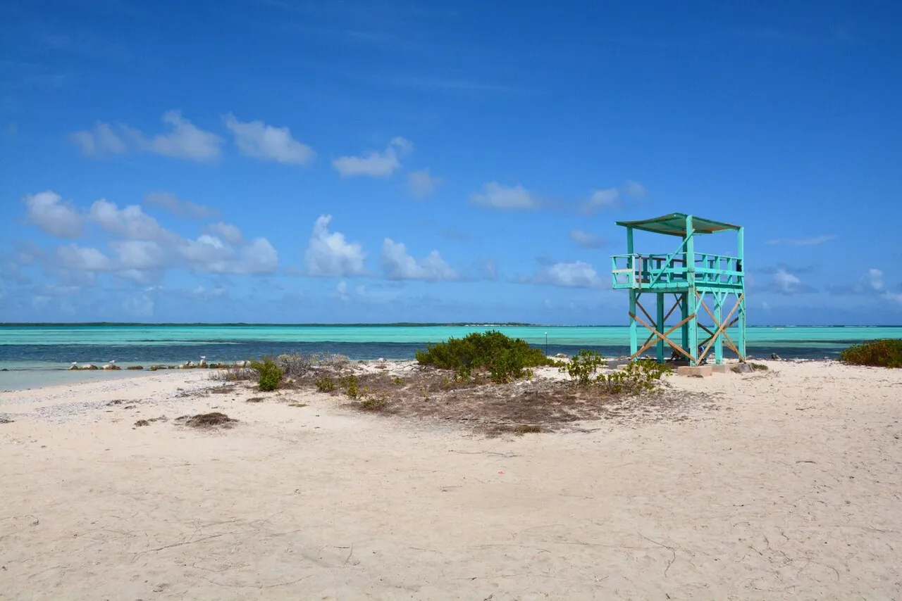 Wit strand aan Lac Bay met een turquoise uitkijktoren en ondiep turquoise water