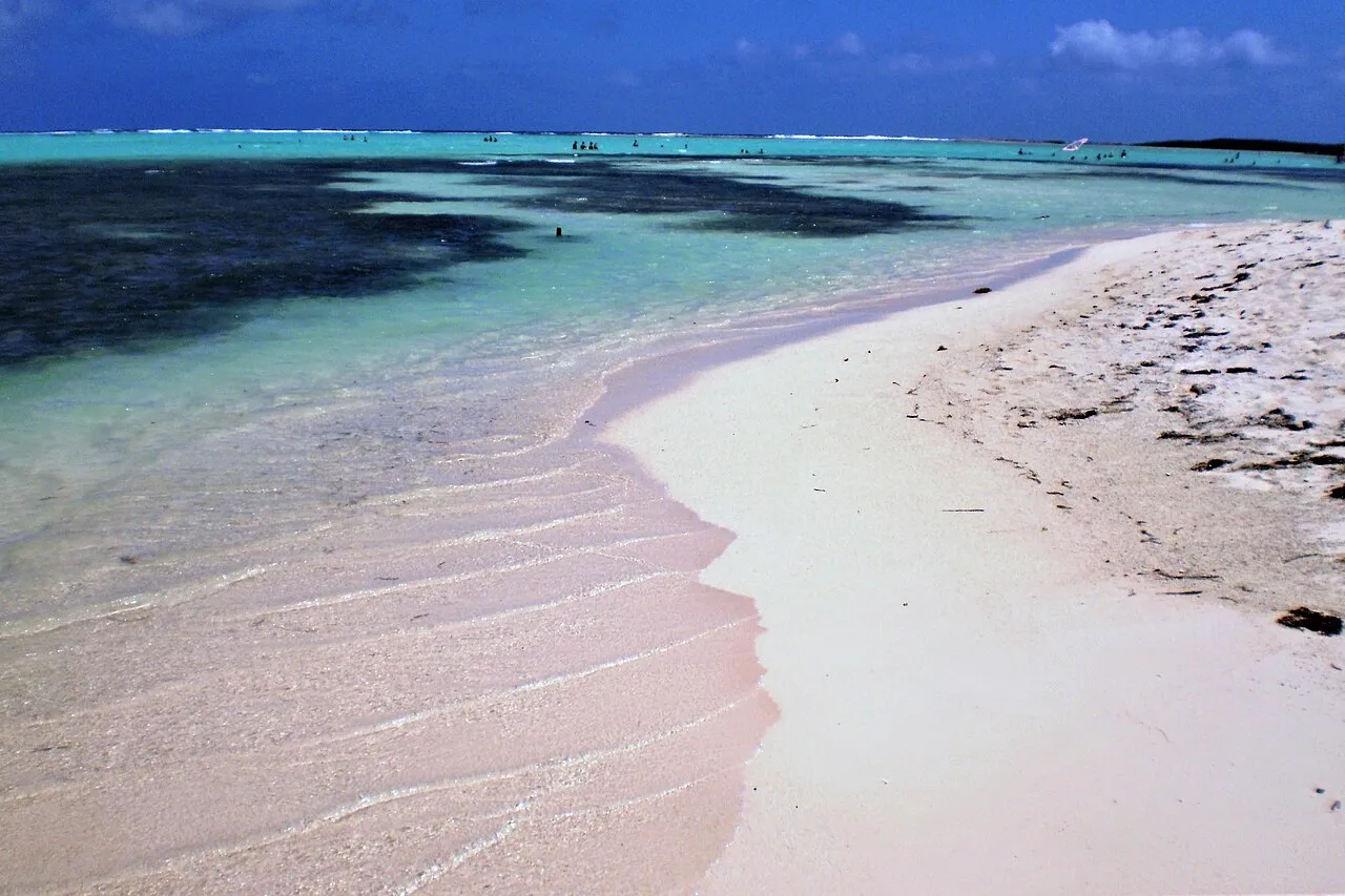 Wit zandstrand van Sorobon met ondiep turquoise water en zeegras in de baai