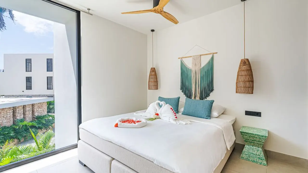 Slaapkamer met kingsize bed en plafondventilator in het Royal Residence 2-kamerappartement van Van der Valk Bonaire