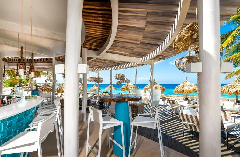 Bar met blauwe toog en barkrukken bij Van der Valk Bonaire, met de zee op de achtergrond