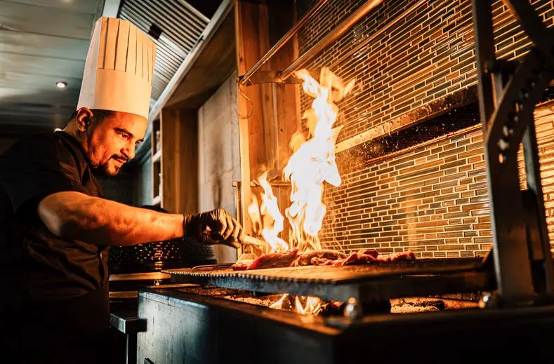 Chef aan de grill met open vuur in het restaurant van Van der Valk Bonaire